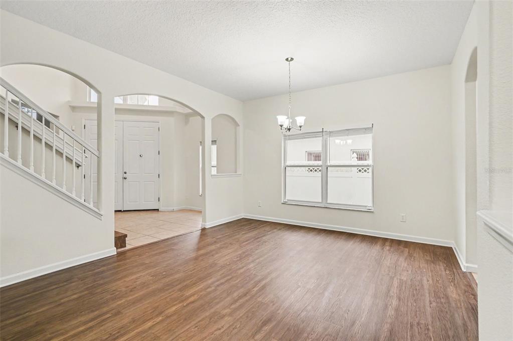 An empty dining room with wood-look flooring, a chandelier, and an arched entryway — 10546 WILLOW RIDGE LOOP, ORLANDO, FL