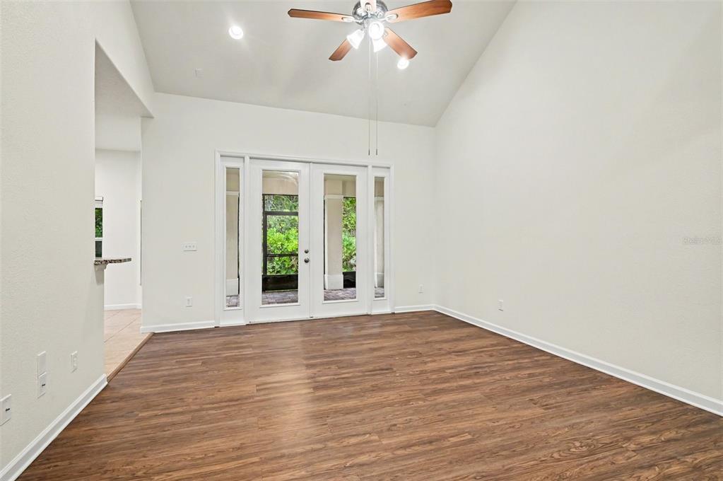 An empty room with wood-look flooring, a vaulted ceiling, a ceiling fan, and glass doors — 10546 WILLOW RIDGE LOOP, ORLANDO, FL