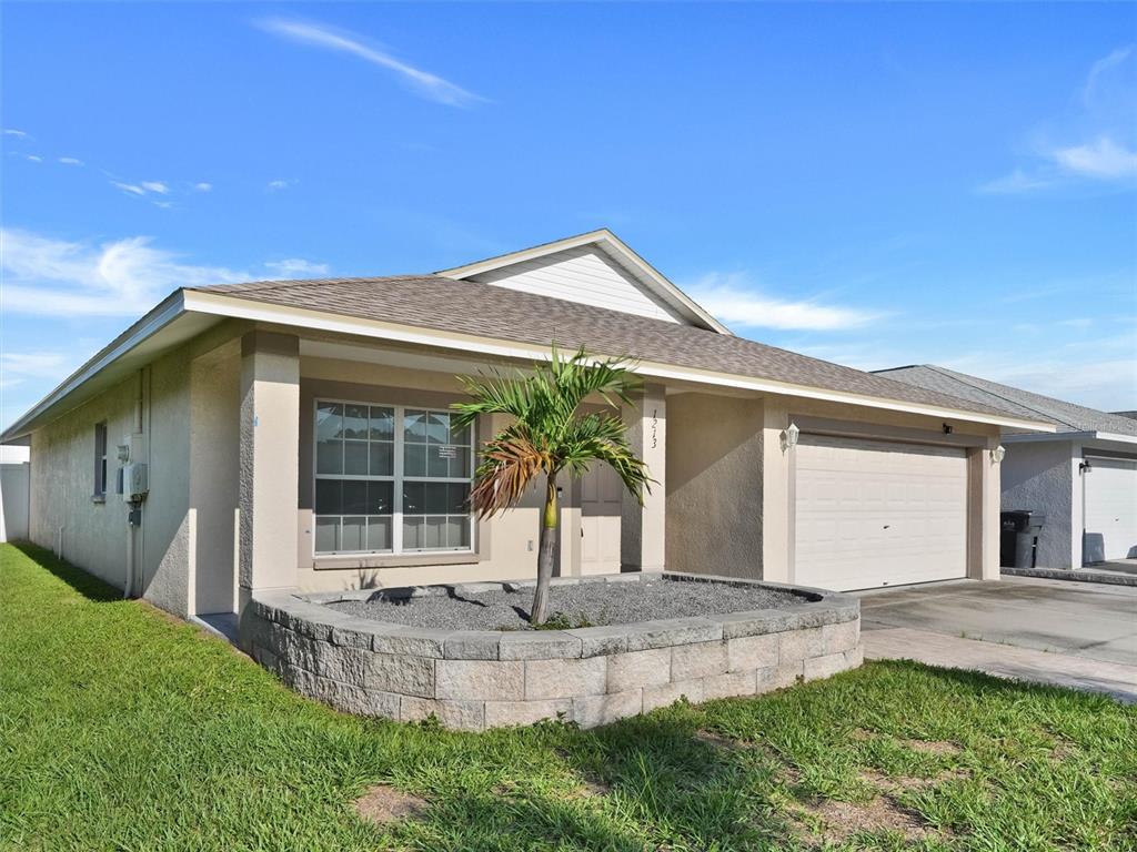 A single-story house with a beige exterior, a two-car garage, and two palm trees — 1213 HUMBLE HAVEN STREET, RUSKIN, FL
