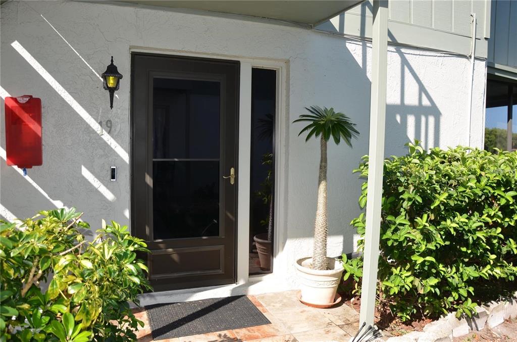 An exterior view of a ground-floor apartment entrance with a staircase and landscaping — 1960 UNION STREET UNIT 19, CLEARWATER, FL