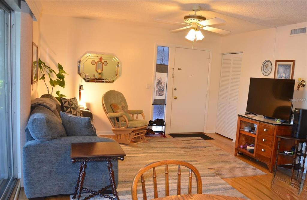 A living room features a blue sofa, a rocking chair, and a television on a stand — 1960 UNION STREET UNIT 19, CLEARWATER, FL