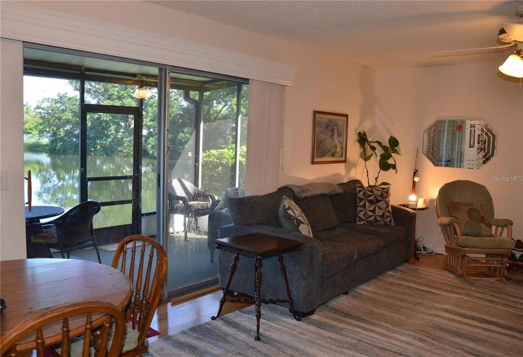 A living room features a grey sofa, a wooden rocking chair, and a screened-in porch — 1960 UNION STREET UNIT 19, CLEARWATER, FL