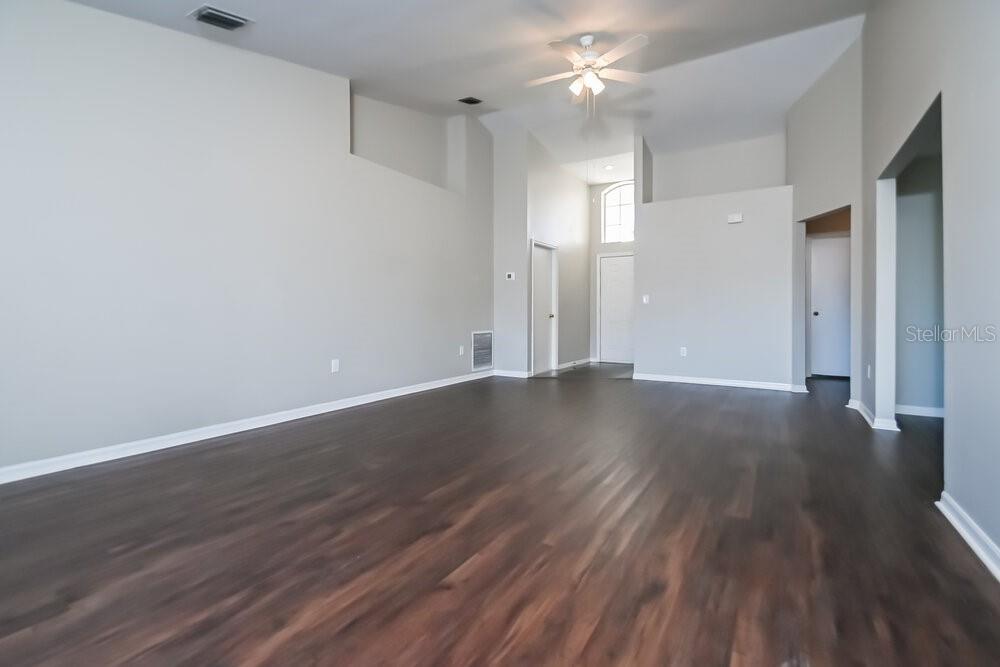 An empty living room with high ceilings, light gray walls, and dark wood-look flooring — 123 LOOKOUT DRIVE, APOLLO BEACH, FL