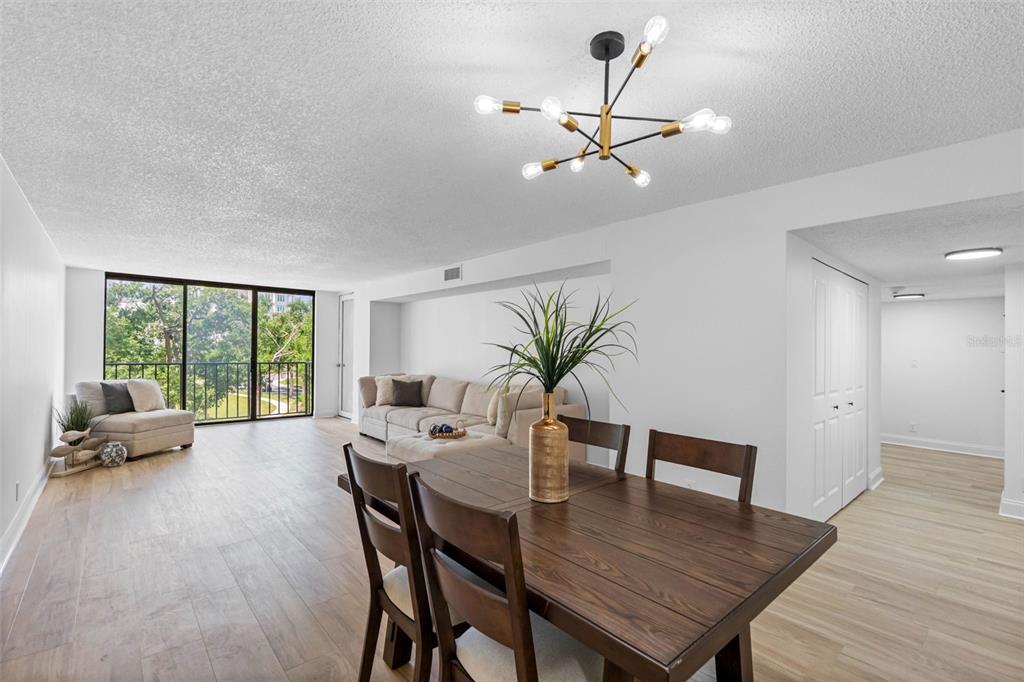 A dining area with a wooden table leads into a living room with balcony access — 220 BELLEVIEW BOULEVARD UNIT 412, BELLEAIR, FL