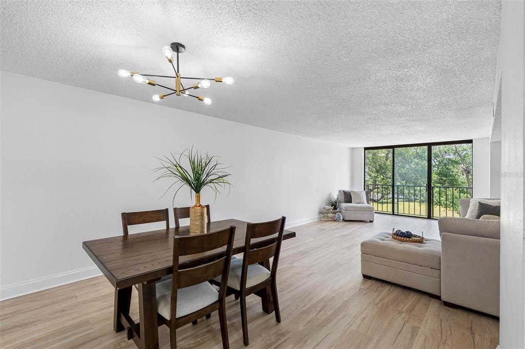 A dining area with a modern chandelier and a living room with floor-to-ceiling windows — 220 BELLEVIEW BOULEVARD UNIT 412, BELLEAIR, FL