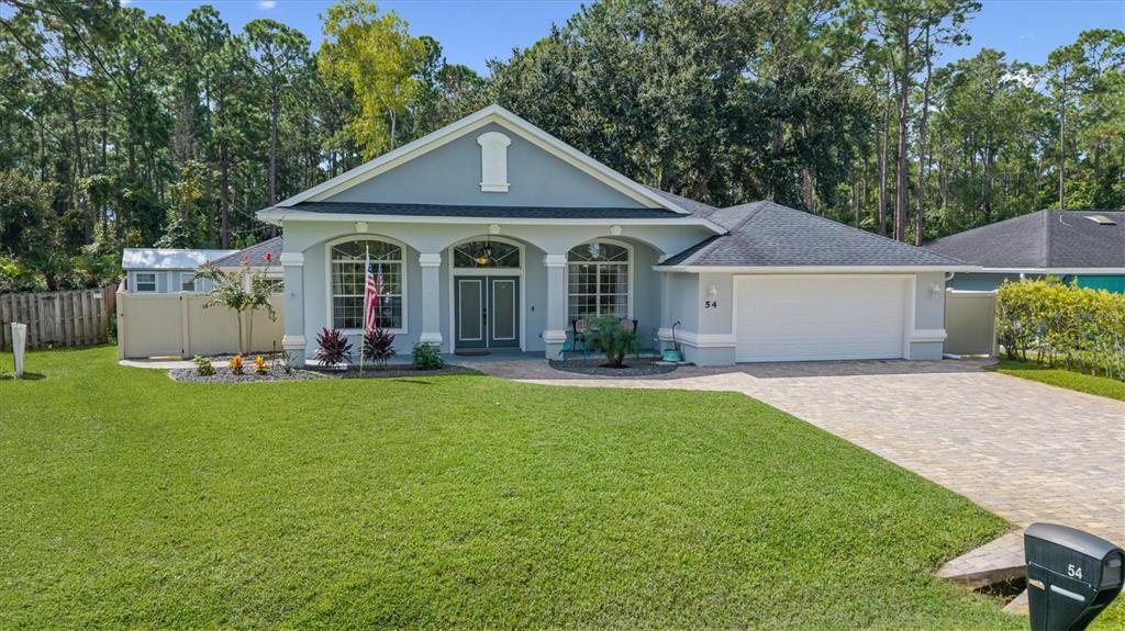 A single-story house with a light blue exterior, arched windows, and a paved driveway — 54 WOODWORTH DRIVE, PALM COAST, FL