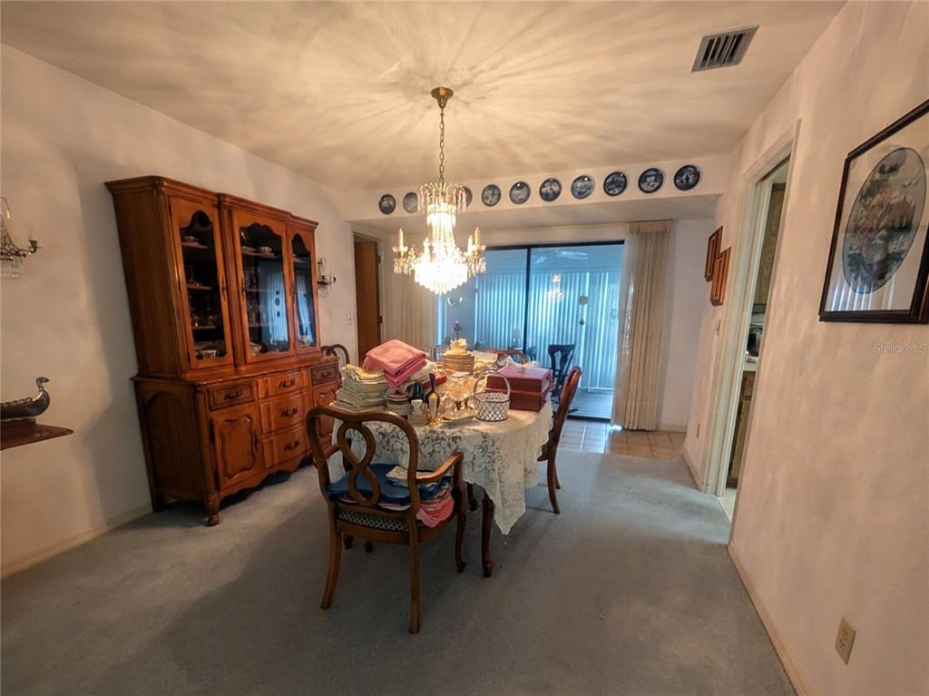 A carpeted living room features a sliding glass door and an adjacent dining area — 7006 120TH STREET, SEMINOLE, FL