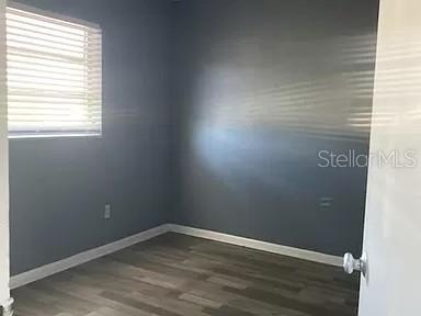 A small, empty bedroom with gray walls, wood-look flooring, and white window blinds — 865 CANADA STREET NE, PALM BAY, FL