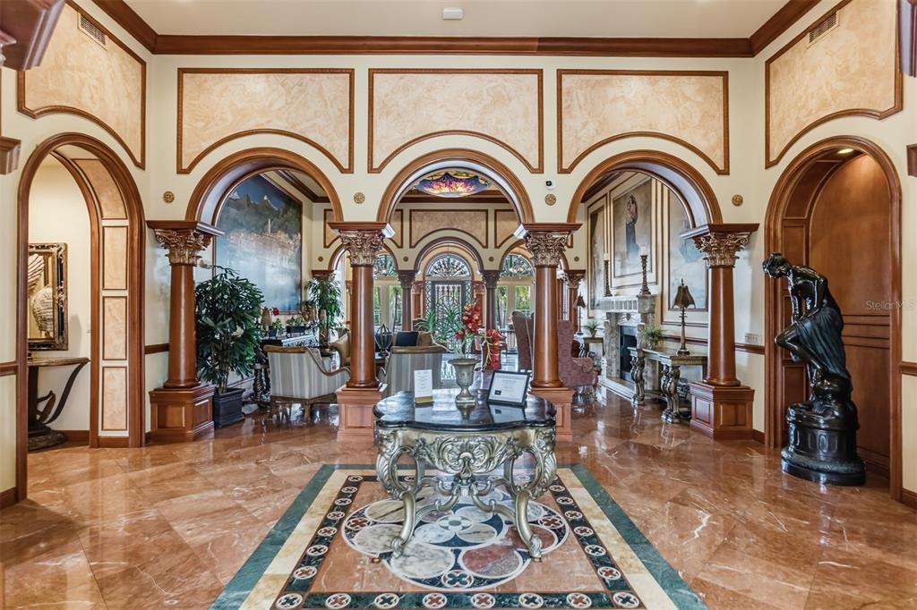 A grand foyer features marble floors, ornate columns, arched doorways, and a central decorative table — 2717 VIA CIPRIANI UNIT 621B, CLEARWATER, FL