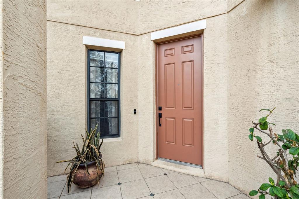A tan stucco entryway features a brown six-panel front door and a tall narrow window — 4867 SWEET CEDAR CIRCLE, ORLANDO, FL