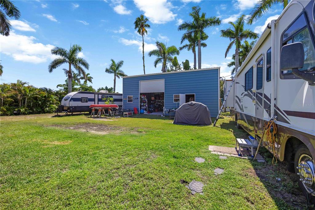 A blue metal workshop stands in a grassy yard between two parked recreational vehicles — 2507 RIVERVIEW BOULEVARD, BRADENTON, FL