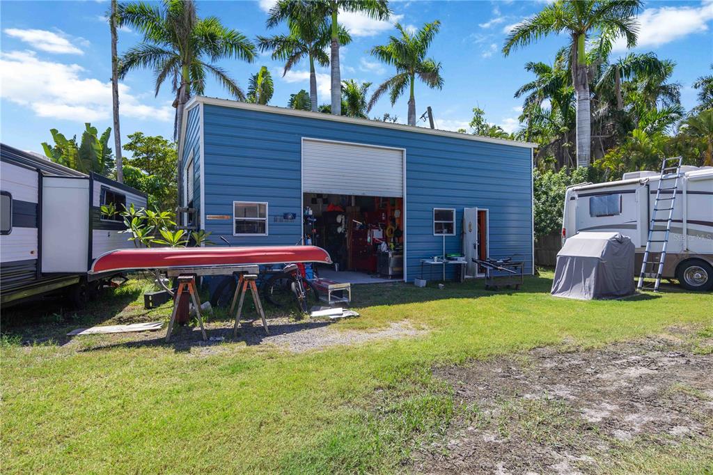 A blue metal workshop building stands in a grassy yard with two parked recreational vehicles — 2507 RIVERVIEW BOULEVARD, BRADENTON, FL