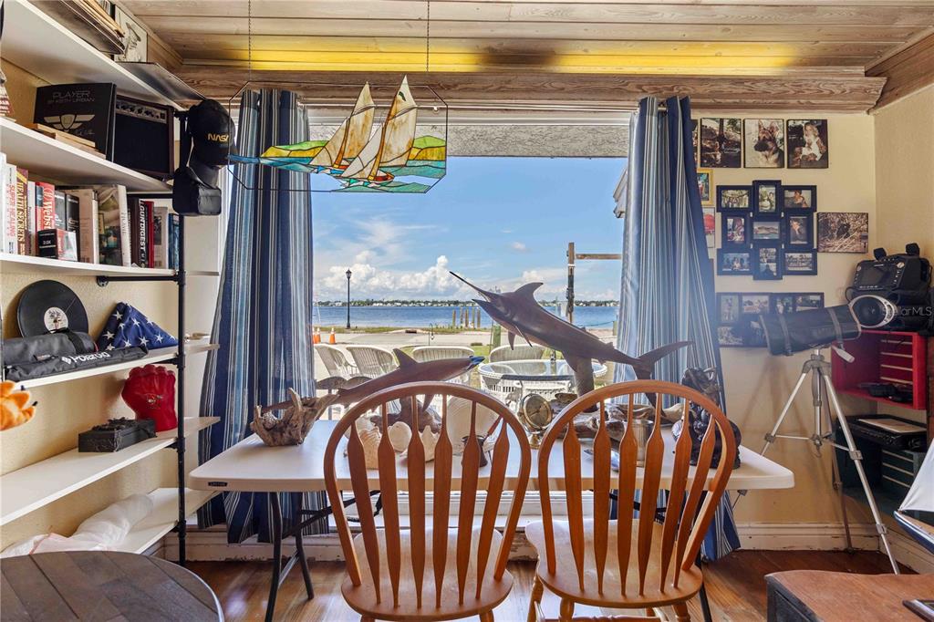 A dining area features a table with two wooden chairs facing a large waterfront window — 2507 RIVERVIEW BOULEVARD, BRADENTON, FL