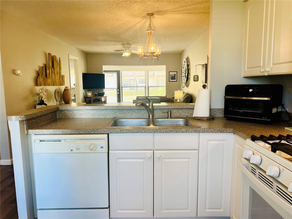 A kitchen with white cabinets, a double sink, and a view into the living room — 2955 FLINT DRIVE S, CLEARWATER, FL