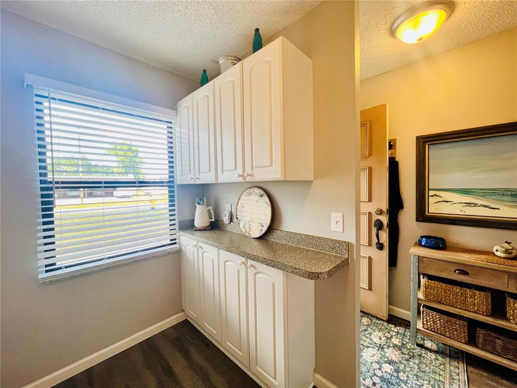 A kitchen area features white cabinets, a speckled countertop, and a window with blinds — 2955 FLINT DRIVE S, CLEARWATER, FL