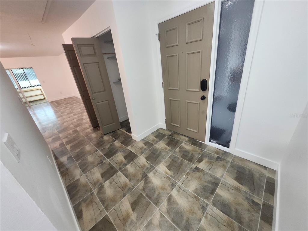 An entryway with a tan door, tiled floor, and an open closet door — 1513 16TH CIRCLE SE UNIT 43, LARGO, FL