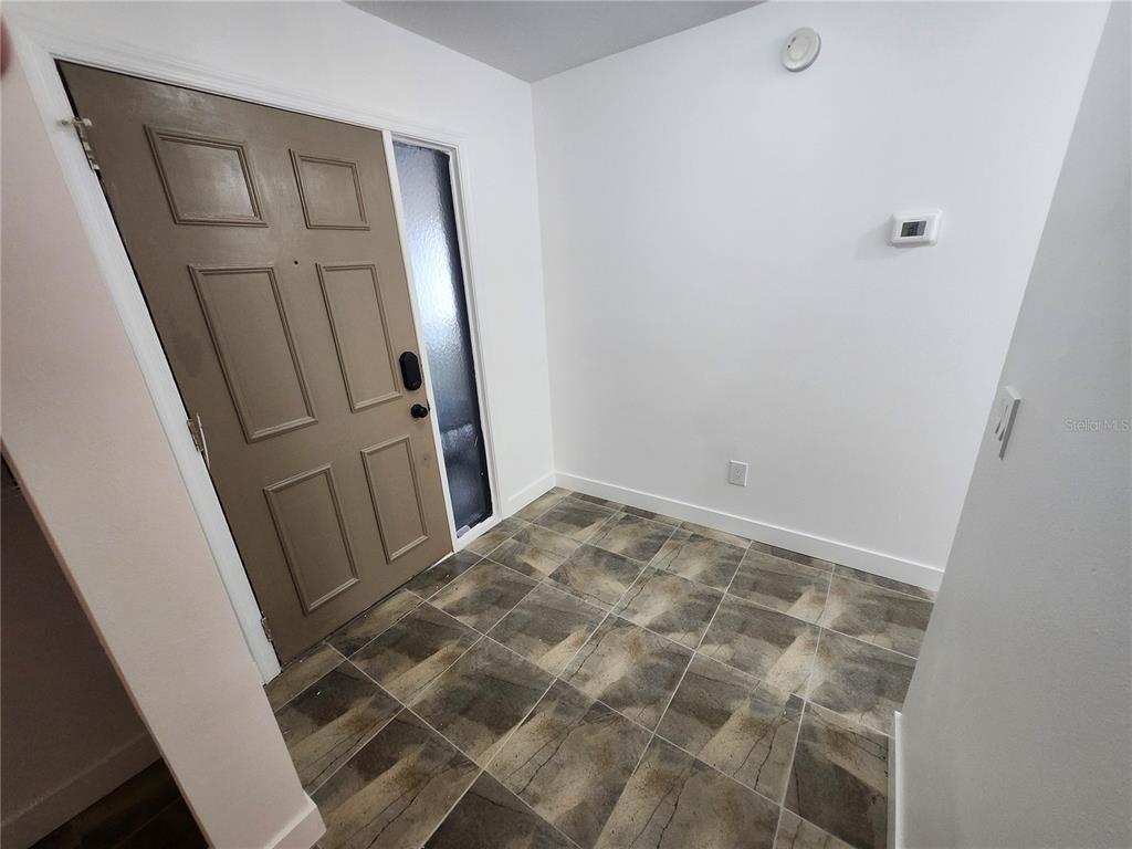 An entryway features a brown front door with a sidelight and patterned tile flooring — 1513 16TH CIRCLE SE UNIT 43, LARGO, FL