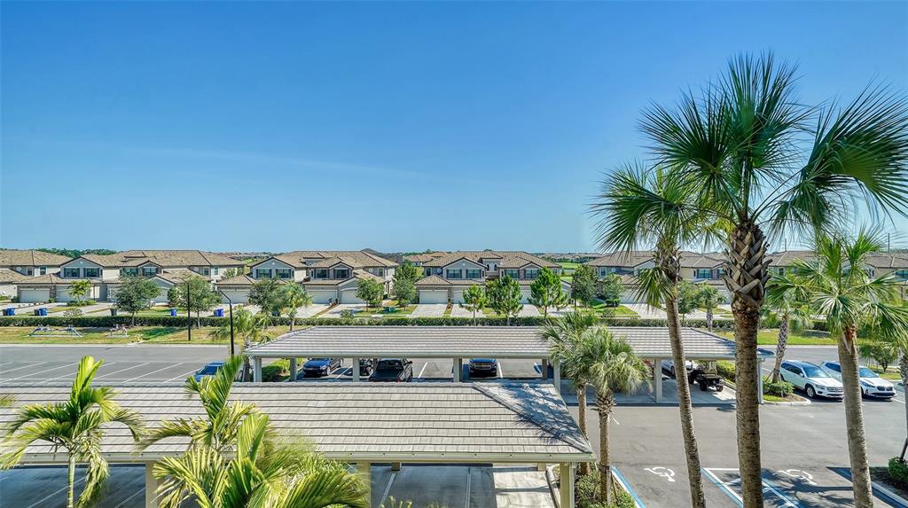 An elevated view shows a parking lot with covered carports and residential buildings in the background — 18028 GAWTHROP DRIVE UNIT 306, BRADENTON, FL