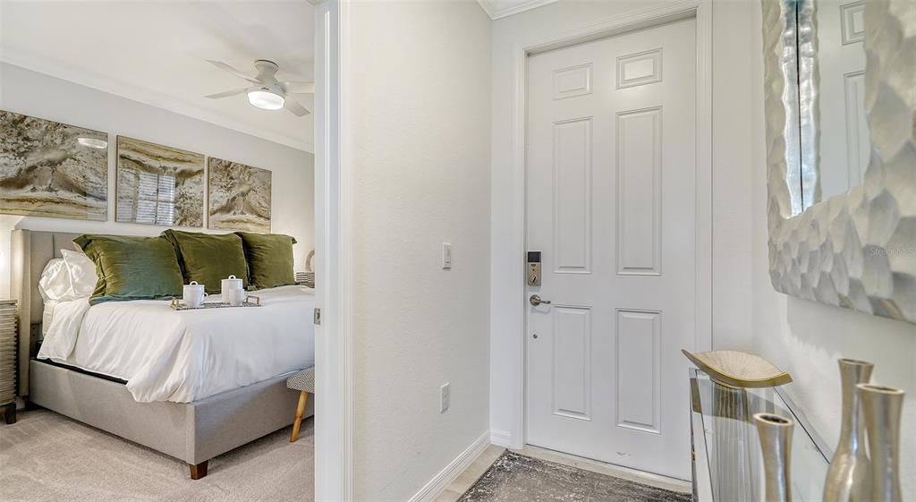 A view from a hallway into a bedroom with a bed and a front door — 18028 GAWTHROP DRIVE UNIT 306, BRADENTON, FL