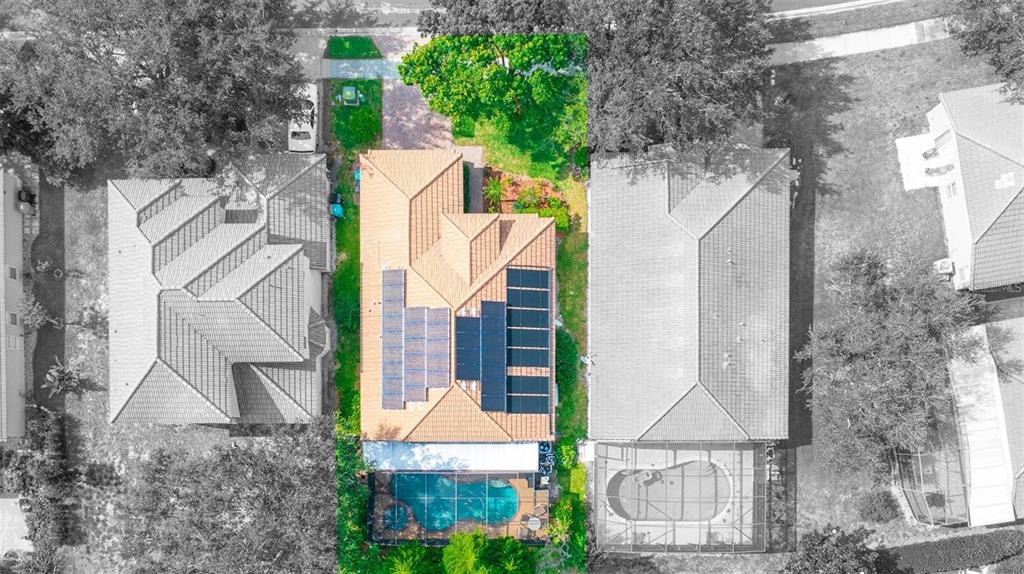 An aerial view shows a house with solar panels on the roof and a screened pool — 5897 BUFORD STREET, ORLANDO, FL