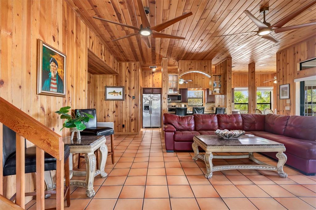 A living room with wood-paneled walls, a red leather sectional, and tile flooring — 51 PALM DRIVE, PLACIDA, FL