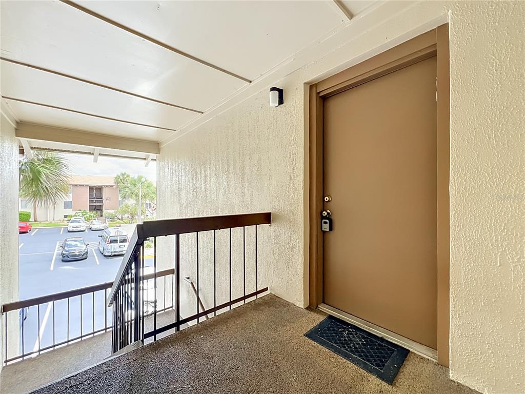 An exterior view of a tan apartment door on a covered walkway with metal railings — 568 ORANGE DRIVE UNIT 50, ALTAMONTE SPRINGS, FL