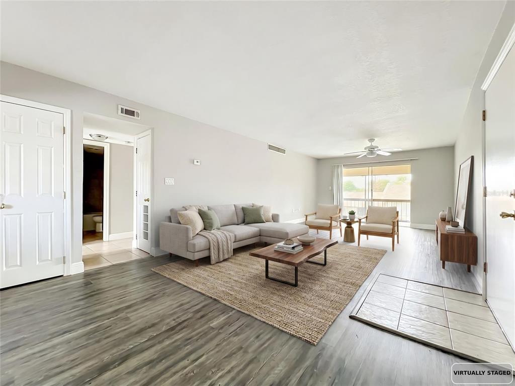 A virtually staged living room features light gray walls, wood-look flooring, and a sliding glass door — 568 ORANGE DRIVE UNIT 50, ALTAMONTE SPRINGS, FL