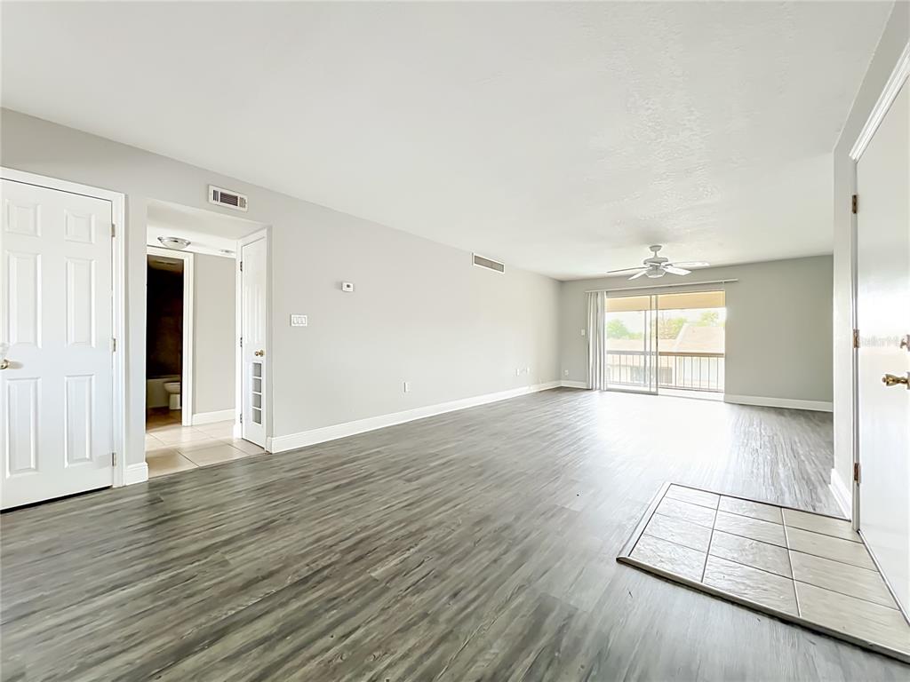 An empty living room features gray wood-look flooring, a ceiling fan, and a sliding glass door — 568 ORANGE DRIVE UNIT 50, ALTAMONTE SPRINGS, FL