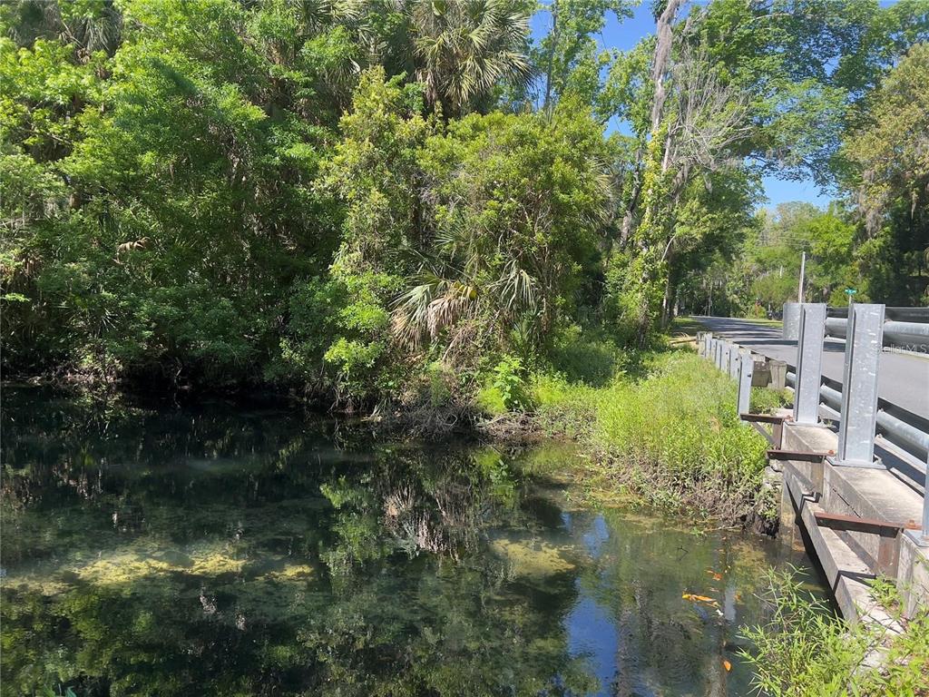 A view of a clear stream flowing under a bridge next to a wooded area — 450 NW CRYSTAL STREET, CRYSTAL RIVER, FL