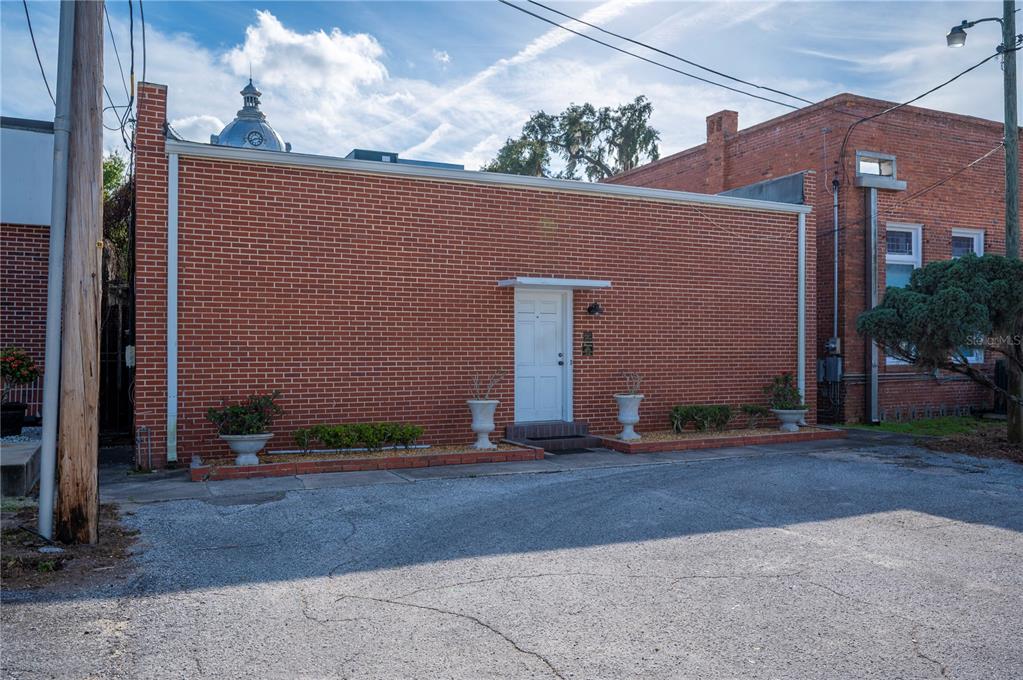 A single-story red brick building features a central white door and decorative planters — 150 E DAVIDSON STREET, BARTOW, FL