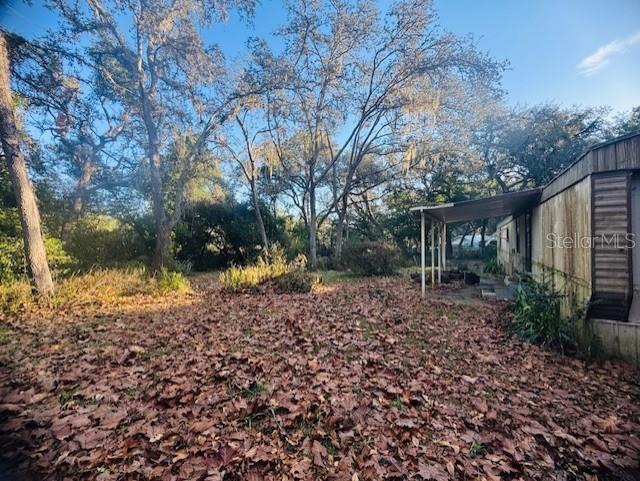 A yard covered in fallen leaves sits beside a mobile home with a covered porch — 4547 CR 692, WEBSTER, FL