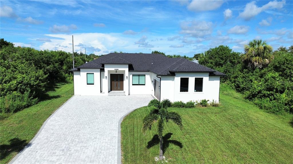 A white single-story house with a dark roof and a paved driveway sits on grass — 4317 MEAGER CIRCLE, PORT CHARLOTTE, FL