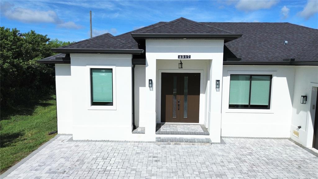 A modern white house exterior features a dark double door entrance and a paved driveway — 4317 MEAGER CIRCLE, PORT CHARLOTTE, FL