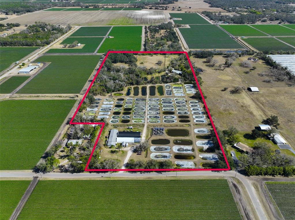 An aerial view shows a rural property with numerous small ponds and agricultural structures — 20112 HOBBS ROAD, WIMAUMA, FL
