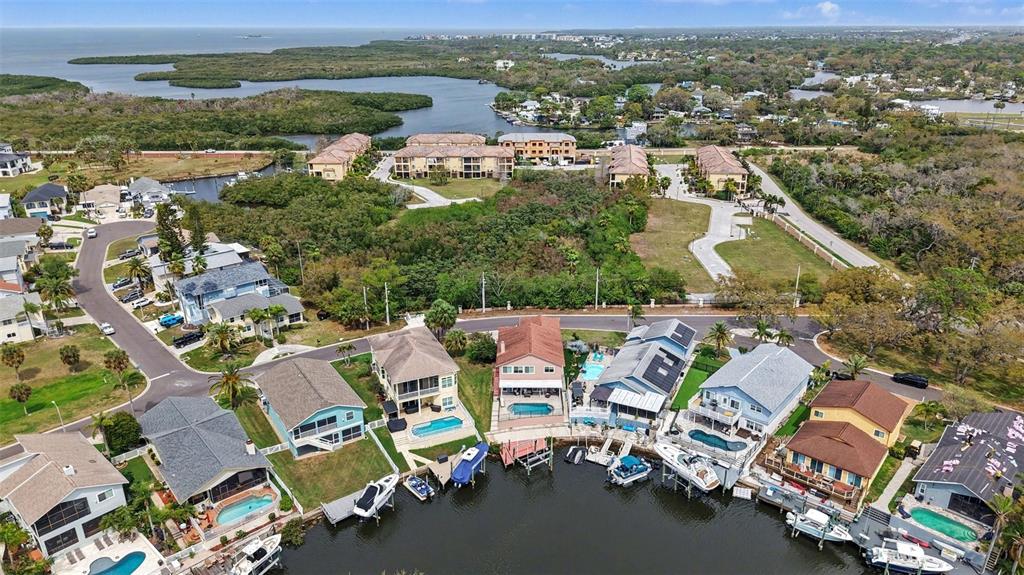 A covered patio overlooks a swimming pool and a canal with houses in the background — 6340 SPOONBILL DRIVE, NEW PORT RICHEY, FL