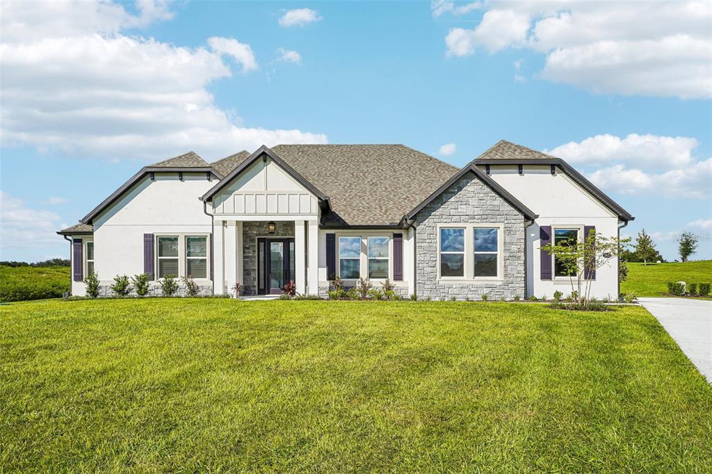 A single-story house with a white exterior, stone accents, and a gray shingled roof — 3832 SADDLE HILL TRAIL, FRUITLAND PARK, FL