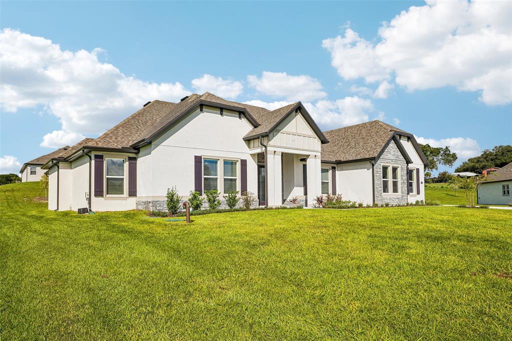 A white single-story house with a gray shingled roof sits on a large grassy lot — 3832 SADDLE HILL TRAIL, FRUITLAND PARK, FL