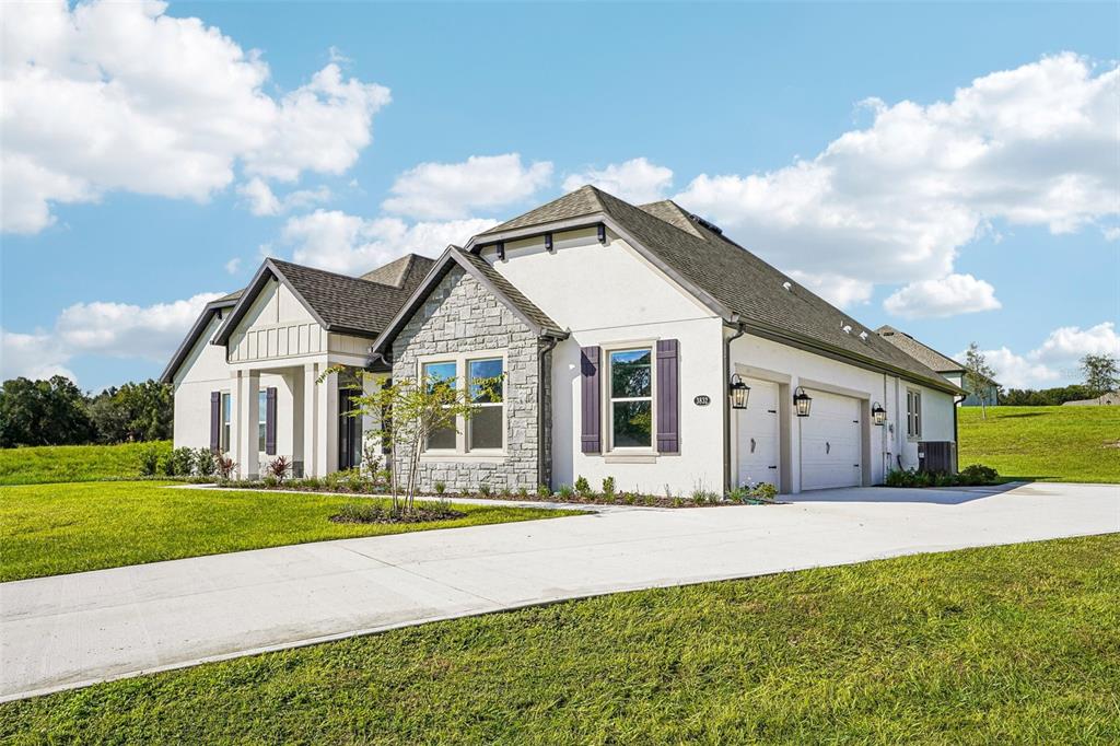 A modern kitchen features white cabinets, a large island with three chairs, and pendant lighting — 3832 SADDLE HILL TRAIL, FRUITLAND PARK, FL