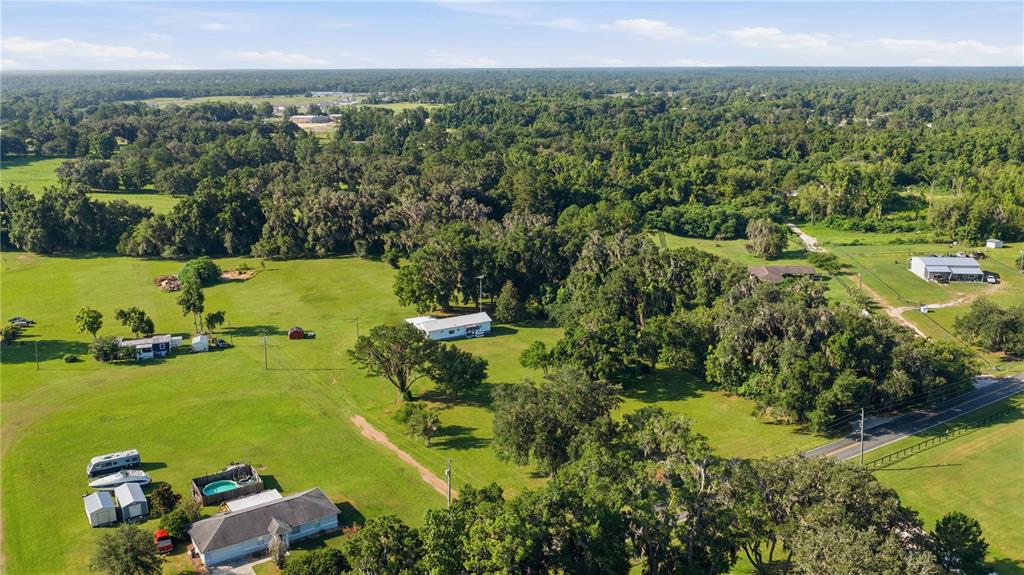 An aerial view shows a house on a large, grassy lot with scattered trees — 4950 SE 112TH STREET ROAD, BELLEVIEW, FL