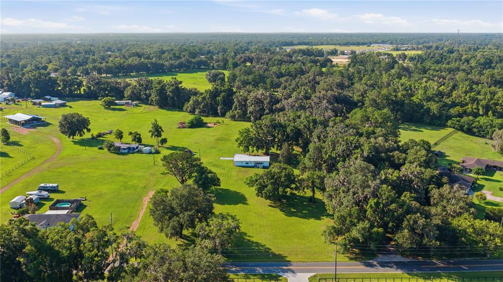 An aerial view shows a rural property with multiple houses, outbuildings, and trees on grass — 4950 SE 112TH STREET ROAD, BELLEVIEW, FL