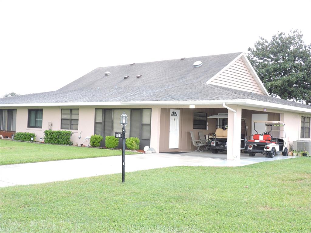 A single-story house with a carport, a golf cart, and a lawn in front — 201 GENESIS POINTE DRIVE UNIT 201, LAKE WALES, FL