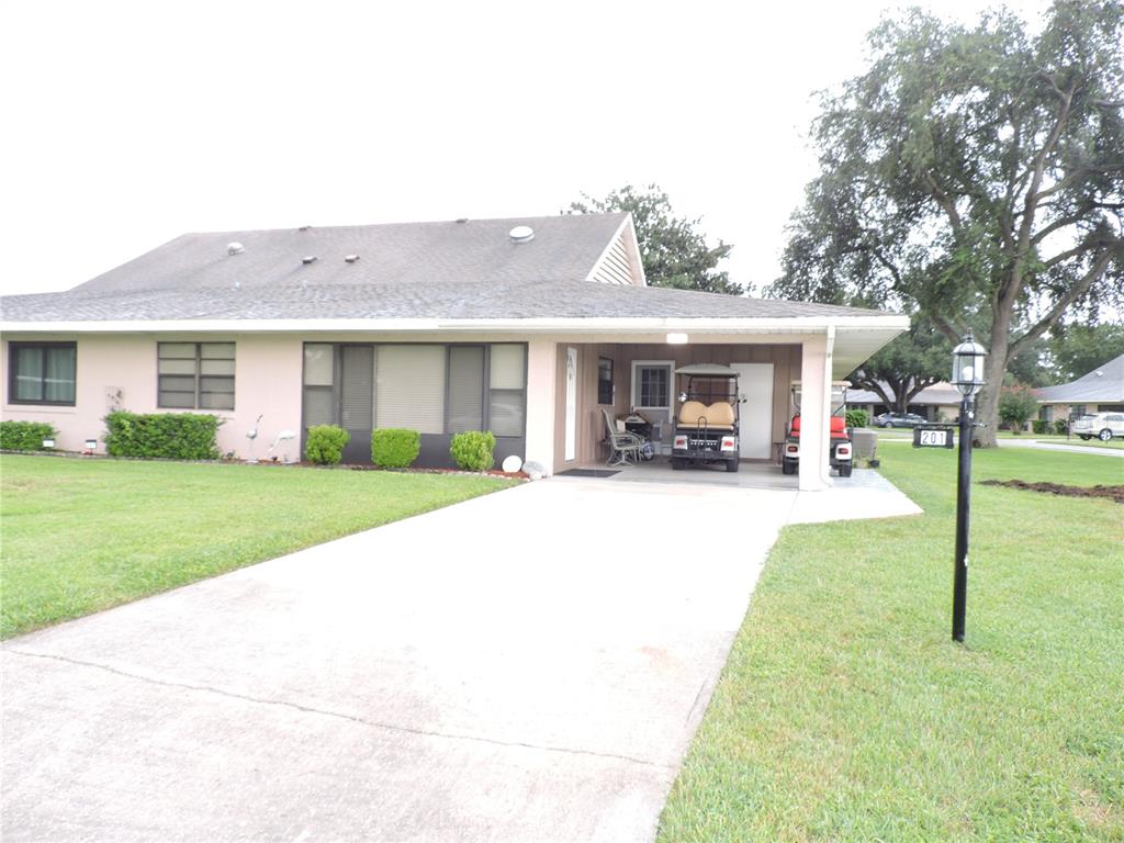 A single-story house with a light pink exterior, a concrete driveway, and a covered carport — 201 GENESIS POINTE DRIVE UNIT 201, LAKE WALES, FL