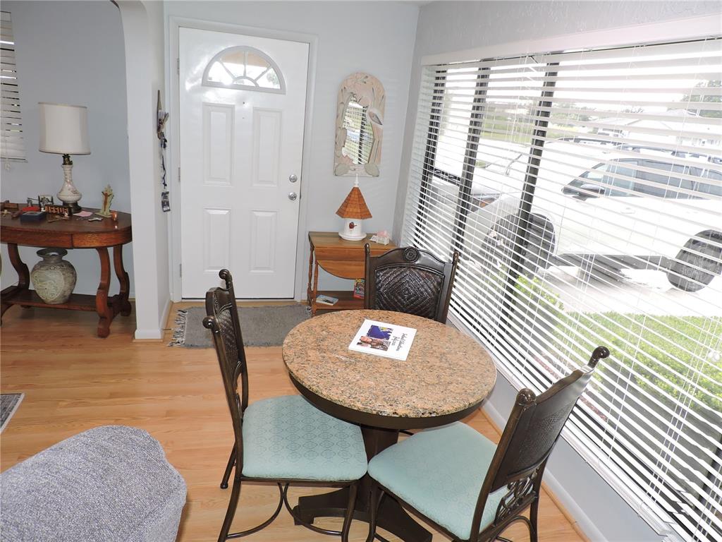 A dining area features a round granite table, two chairs, and a front entryway door — 201 GENESIS POINTE DRIVE UNIT 201, LAKE WALES, FL