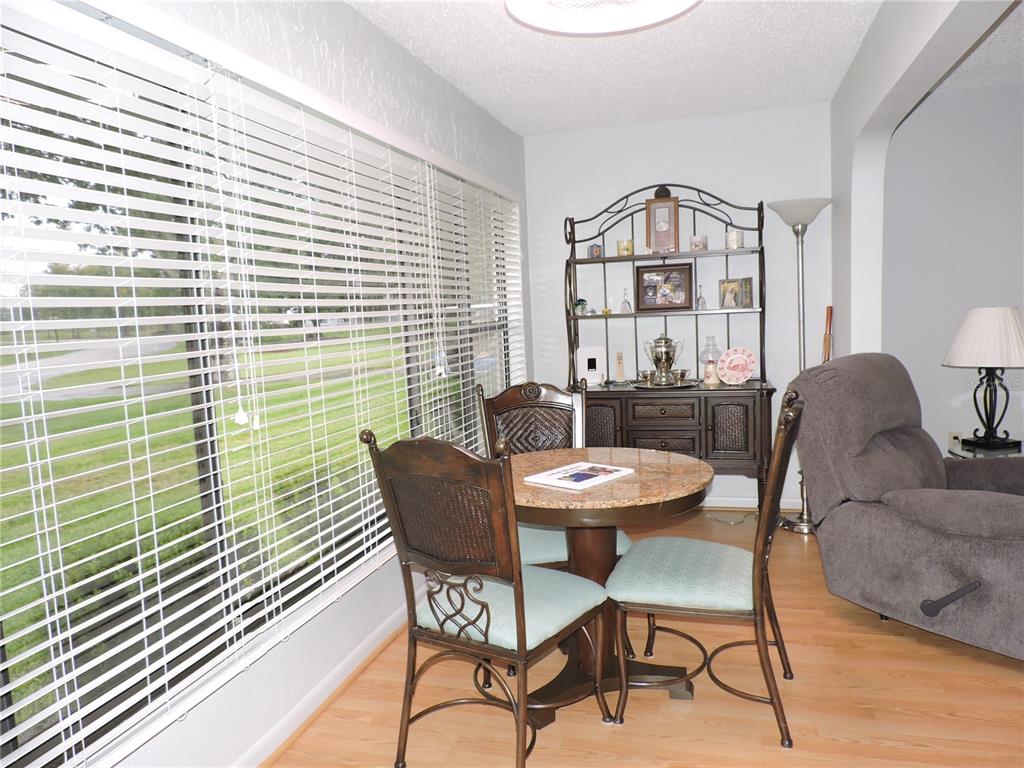 A dining area features a round granite table, metal chairs, and a large window with blinds — 201 GENESIS POINTE DRIVE UNIT 201, LAKE WALES, FL