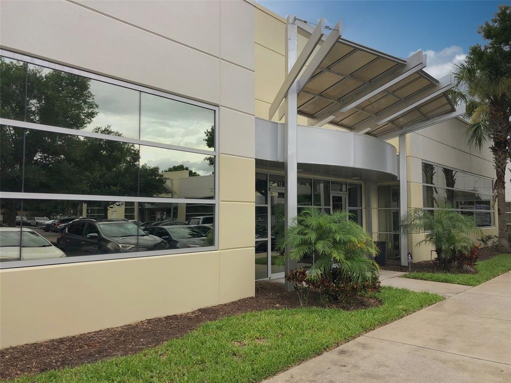 The exterior of a modern commercial building features large glass windows and a metal awning — 8810 COMMODITY CIRCLE UNIT 12, ORLANDO, FL