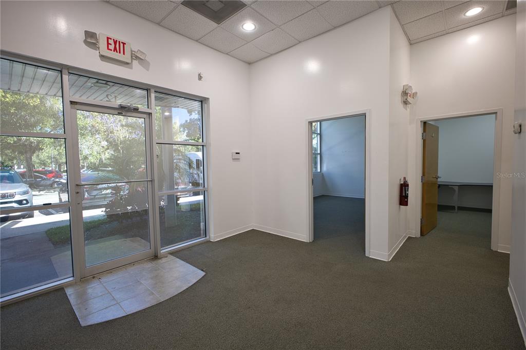 An office interior features a glass entrance door, carpeted flooring, and two open doorways — 8810 COMMODITY CIRCLE UNIT 12, ORLANDO, FL