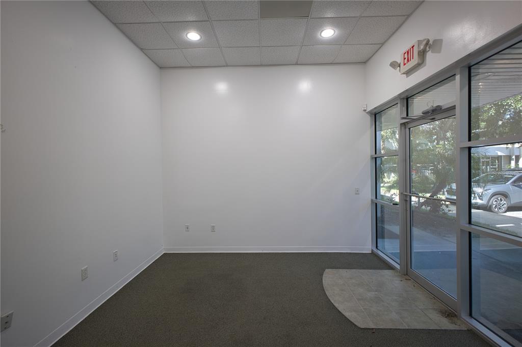 An empty office space features white walls, gray carpeting, recessed ceiling lights, and a glass door — 8810 COMMODITY CIRCLE UNIT 12, ORLANDO, FL