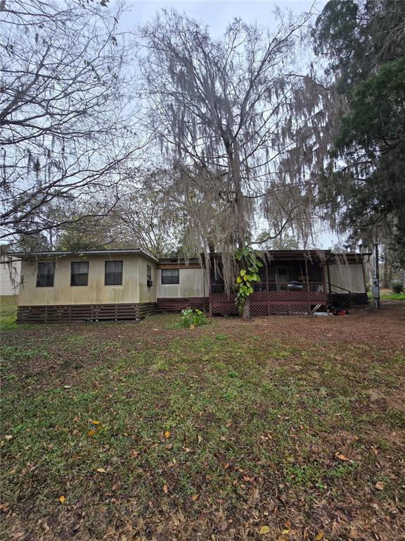 A single-story mobile home with a screened porch and lattice skirting sits on a lawn — 9374 CR 657, BUSHNELL, FL