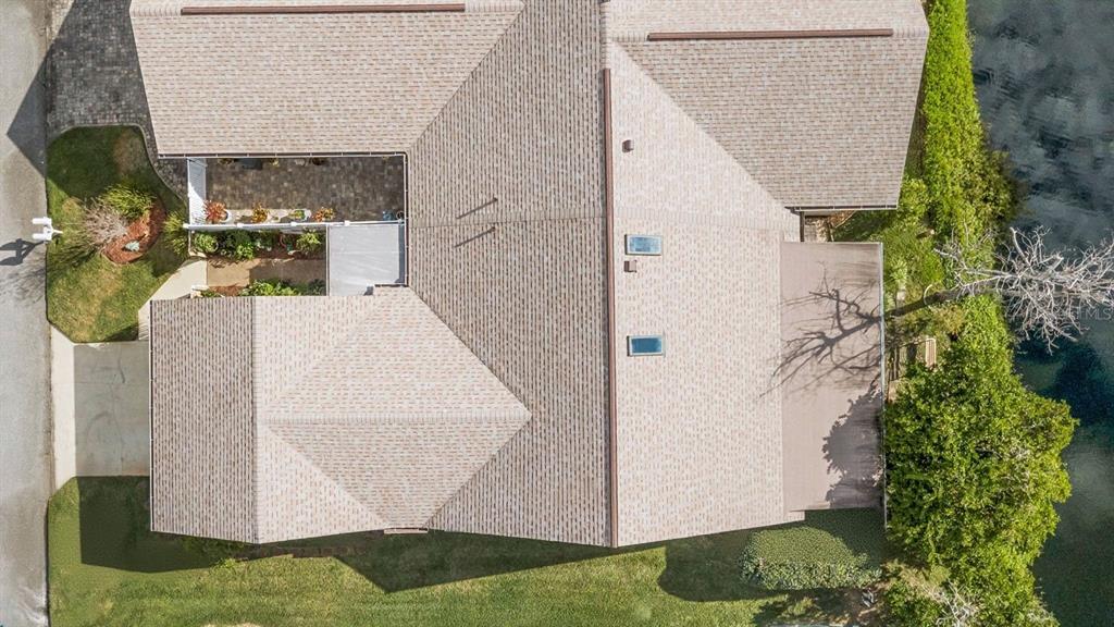 An aerial view shows the roof of a house with a patio and waterfront yard — 44 FORE DRIVE, NEW SMYRNA BEACH, FL
