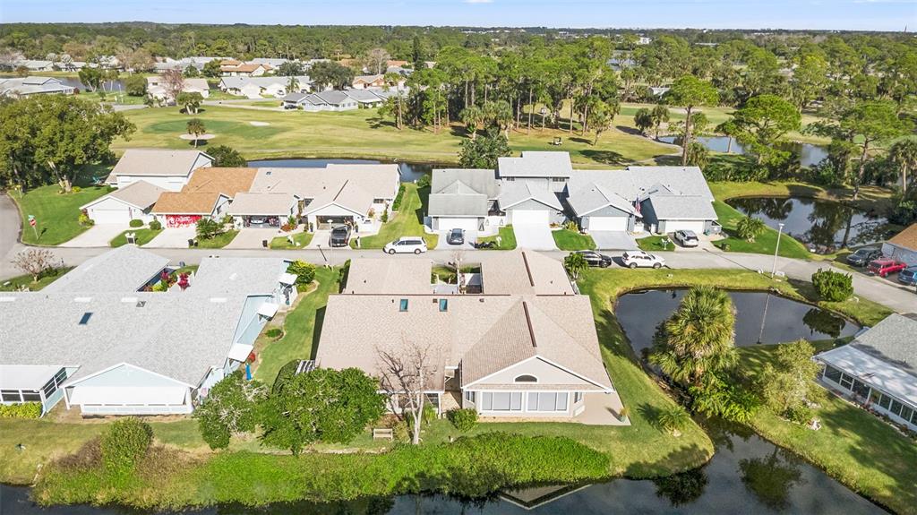An aerial view shows a residential neighborhood with houses, a golf course, and ponds — 44 FORE DRIVE, NEW SMYRNA BEACH, FL